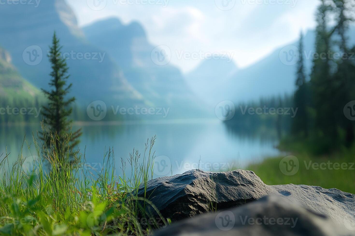 Serene Mountain Lake with Rocky Foreground and Pine Trees Under Bright Sky in Misty Morning Light photo