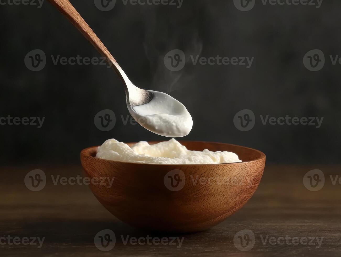 Warm bowl of creamy yogurt with spoon hovering above it photo