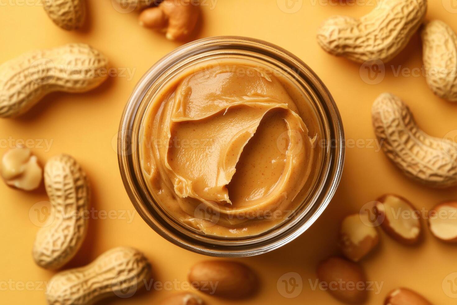 Peanut butter in a jar surrounded by peanuts on an orange background photo