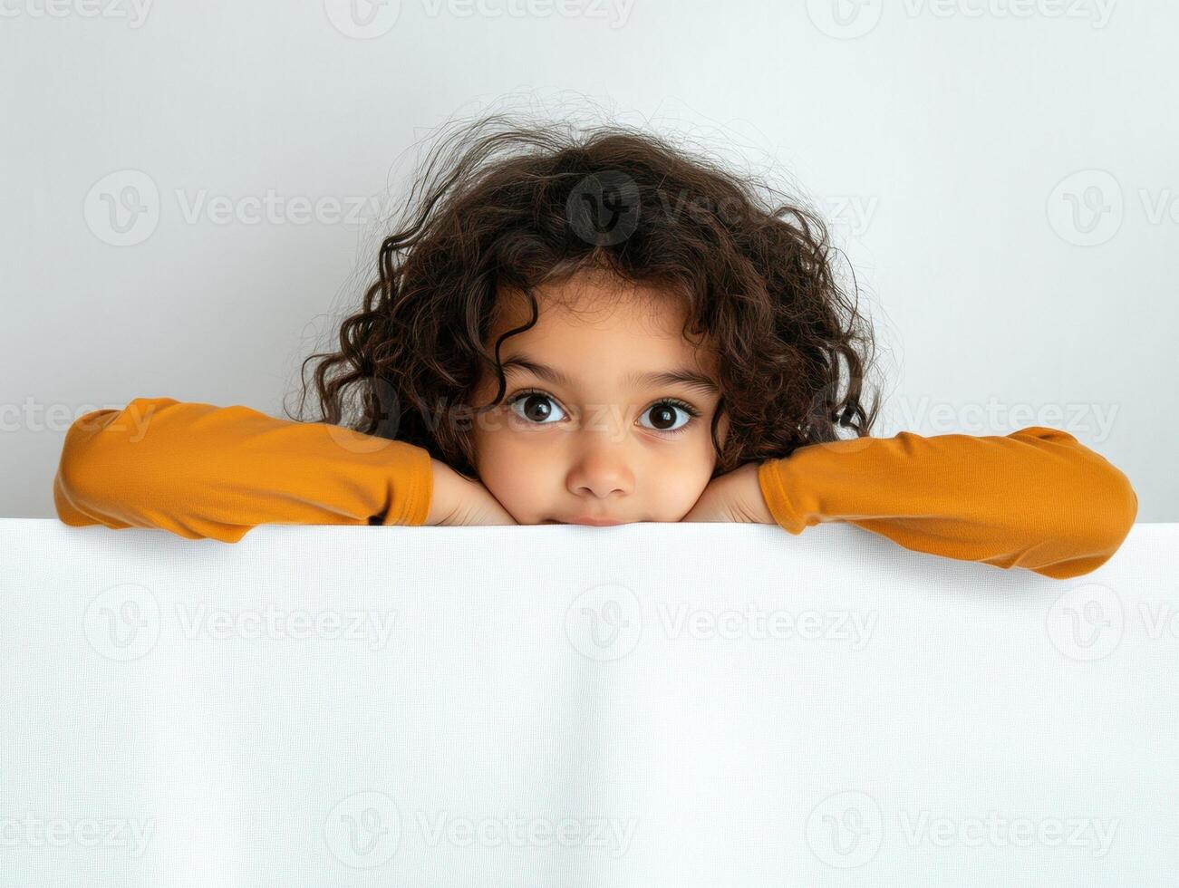Curly-haired child resting on a white surface in a calm setting photo