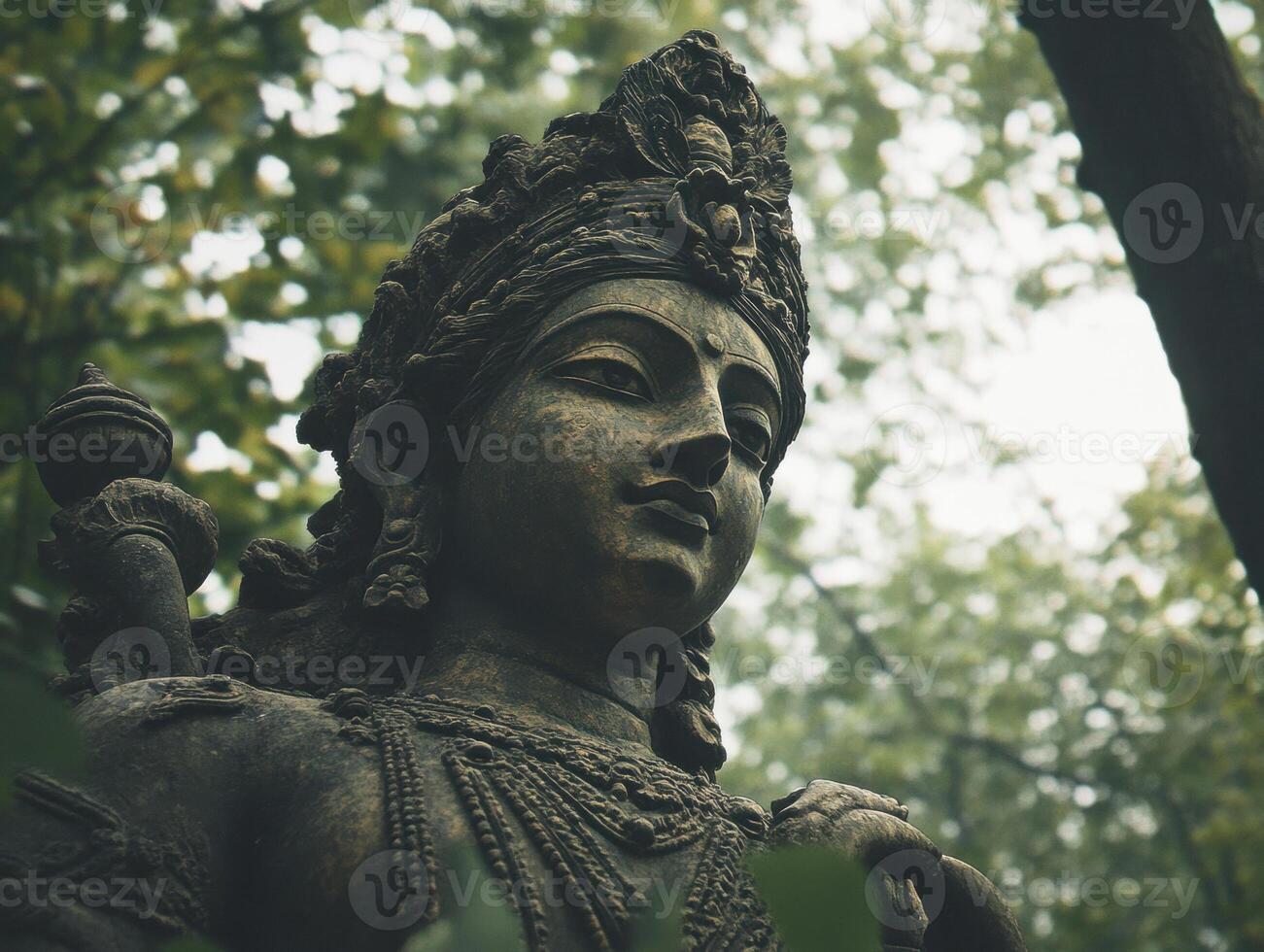 Sculpture of a deity amidst lush greenery in serene forest setting photo