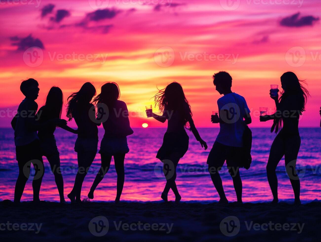 Friends enjoy drinks and dancing at sunset on the beach photo