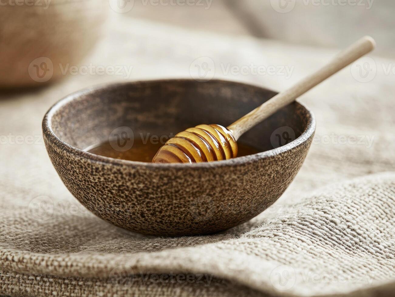 Honey dipper resting in a rustic bowl of golden honey photo