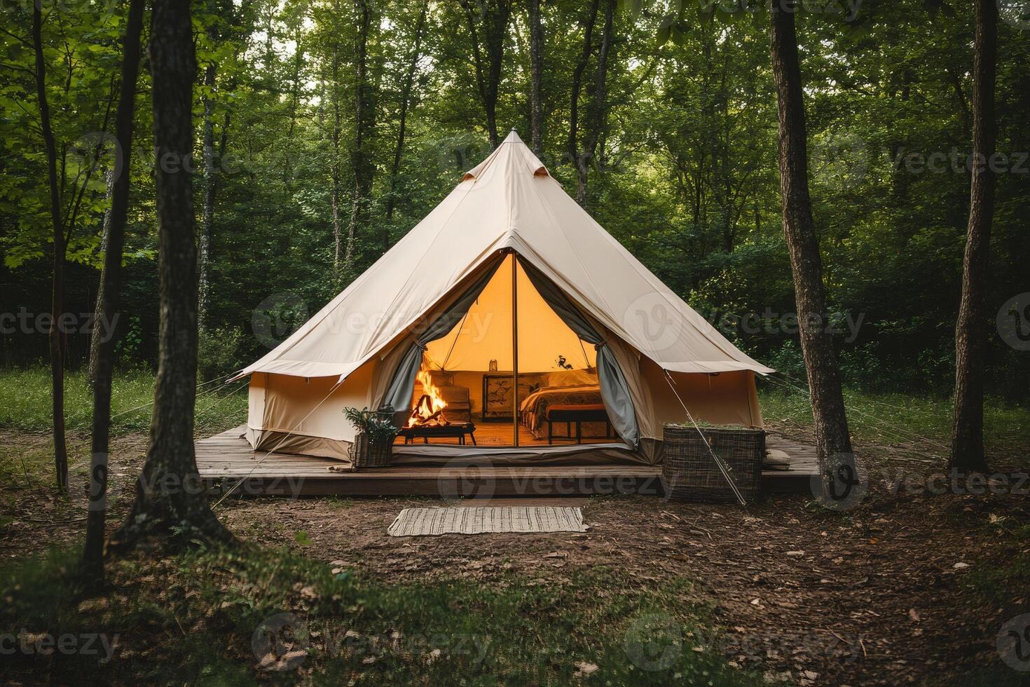 Glamping tent with cozy fireplace illuminating the forest at dusk photo