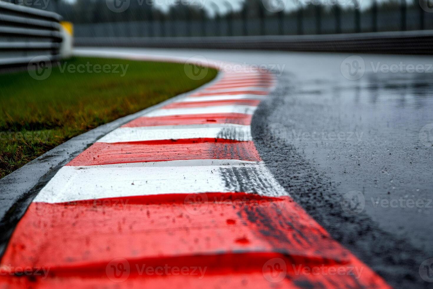 Red and white kerbs defining the edge of a wet racetrack photo