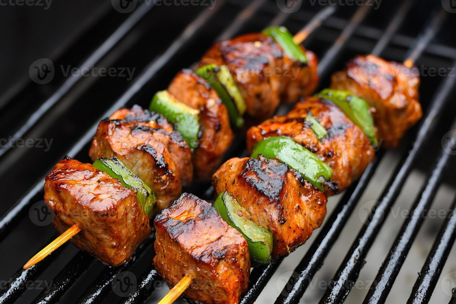 Pork and green bell peppers grilling on skewers on a barbecue photo
