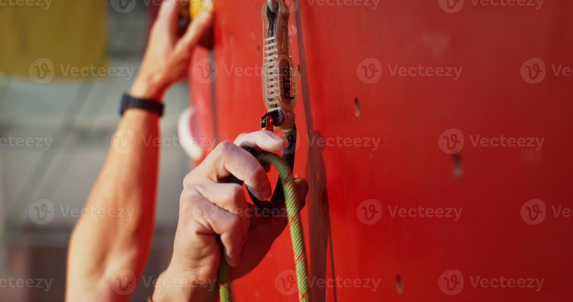 Close-up of securing a lanyard to the hooks on a climbing wall photo