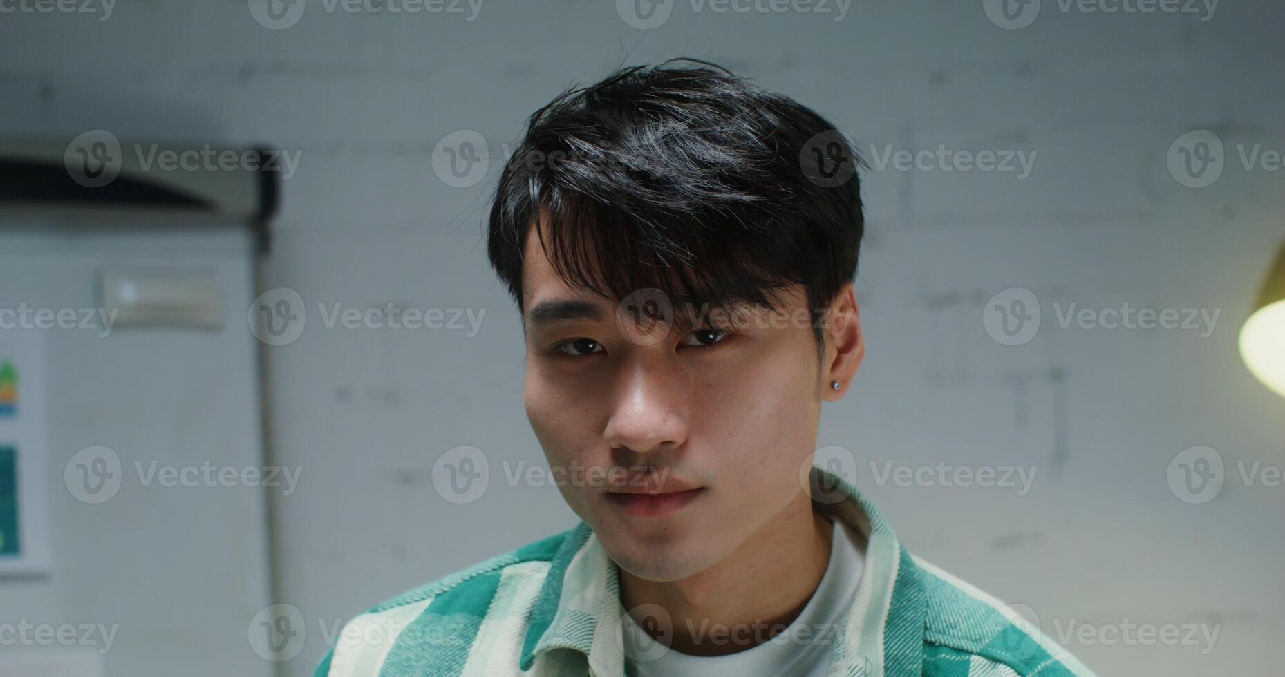 Young asian man of turns his head looking into the camera and smiles photo