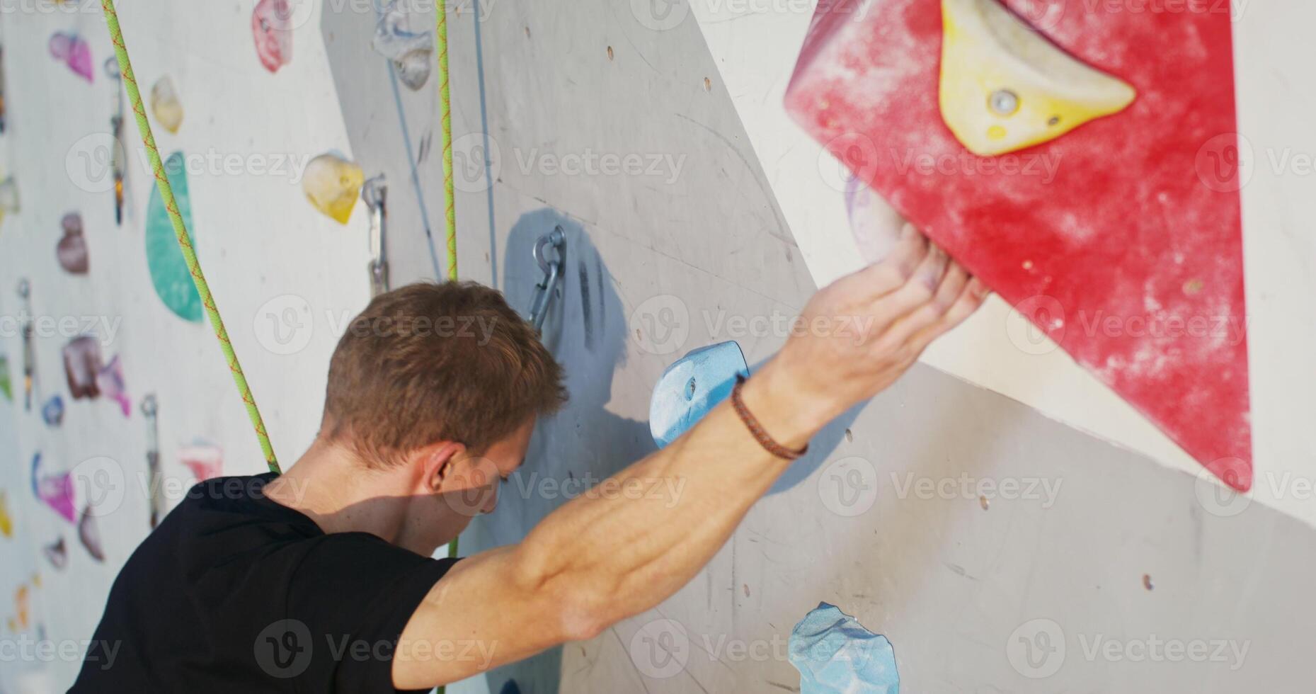 A man climbs up the artificial surface of the climbing wall, striving for top photo