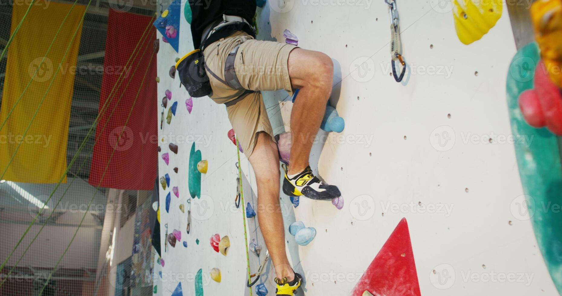 A man is engaged in rock climbing on an artificial surface in an climbing wall photo