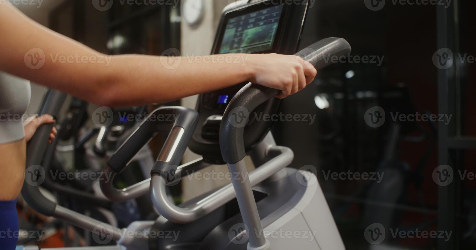 A woman is engaged in an ellipse in an indoor gym, Close-up side view photo