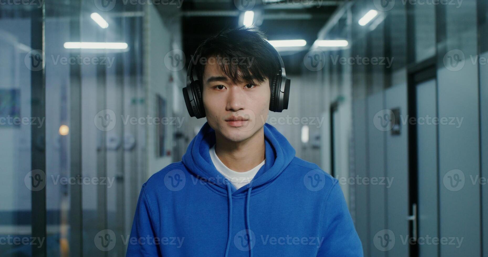 A Asian man with a serious look looks into the camera, standing in the office photo