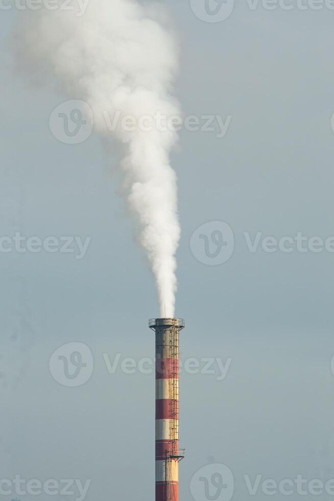 Smoke coming out of factory chimneys causes air pollution to pollute the environment. The chimneys are located around densely populated areas. Industrial waste is dangerous to public health. photo