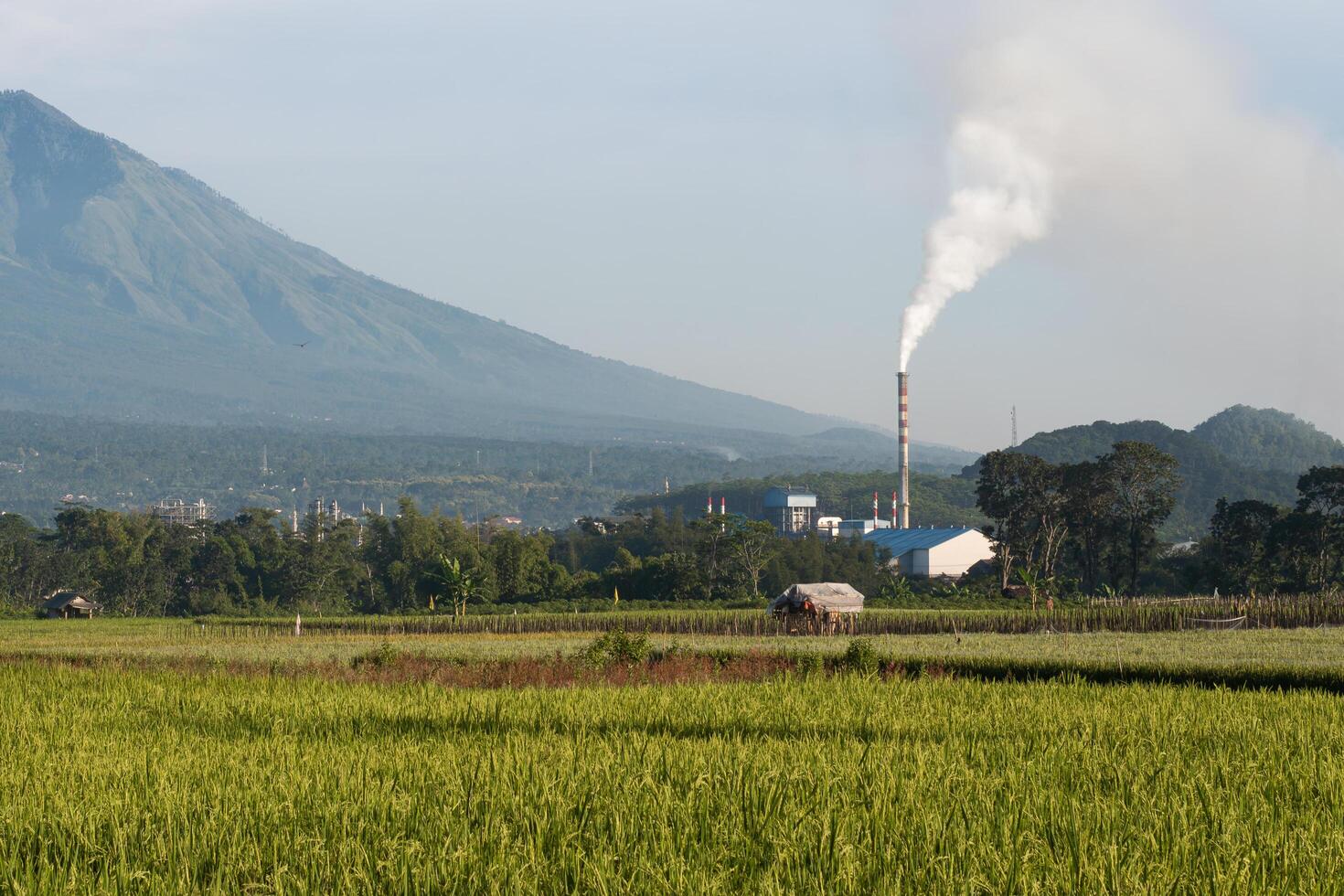 Smoke coming out of factory chimneys causes air pollution to pollute the environment. Chimneys are located around agricultural and mountainous areas. Factory waste is dangerous for public health. photo