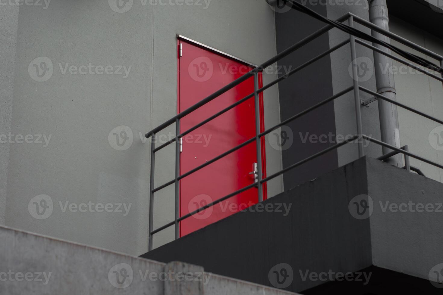 Red emergency door with black iron stairs behind factory building. Industrial fire exit for safety and evacuation. photo