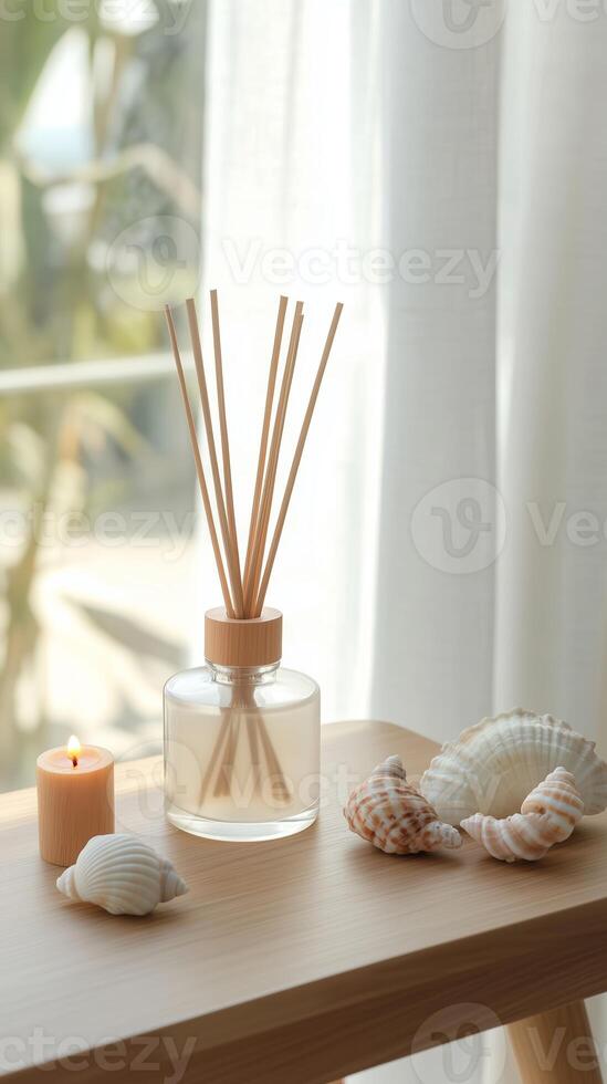Home decor arrangement with reed diffuser, candle, and seashells by the window during daylight photo