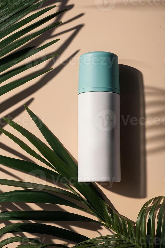 Stylish thermal bottle with teal lid resting on a light background surrounded by tropical leaves photo