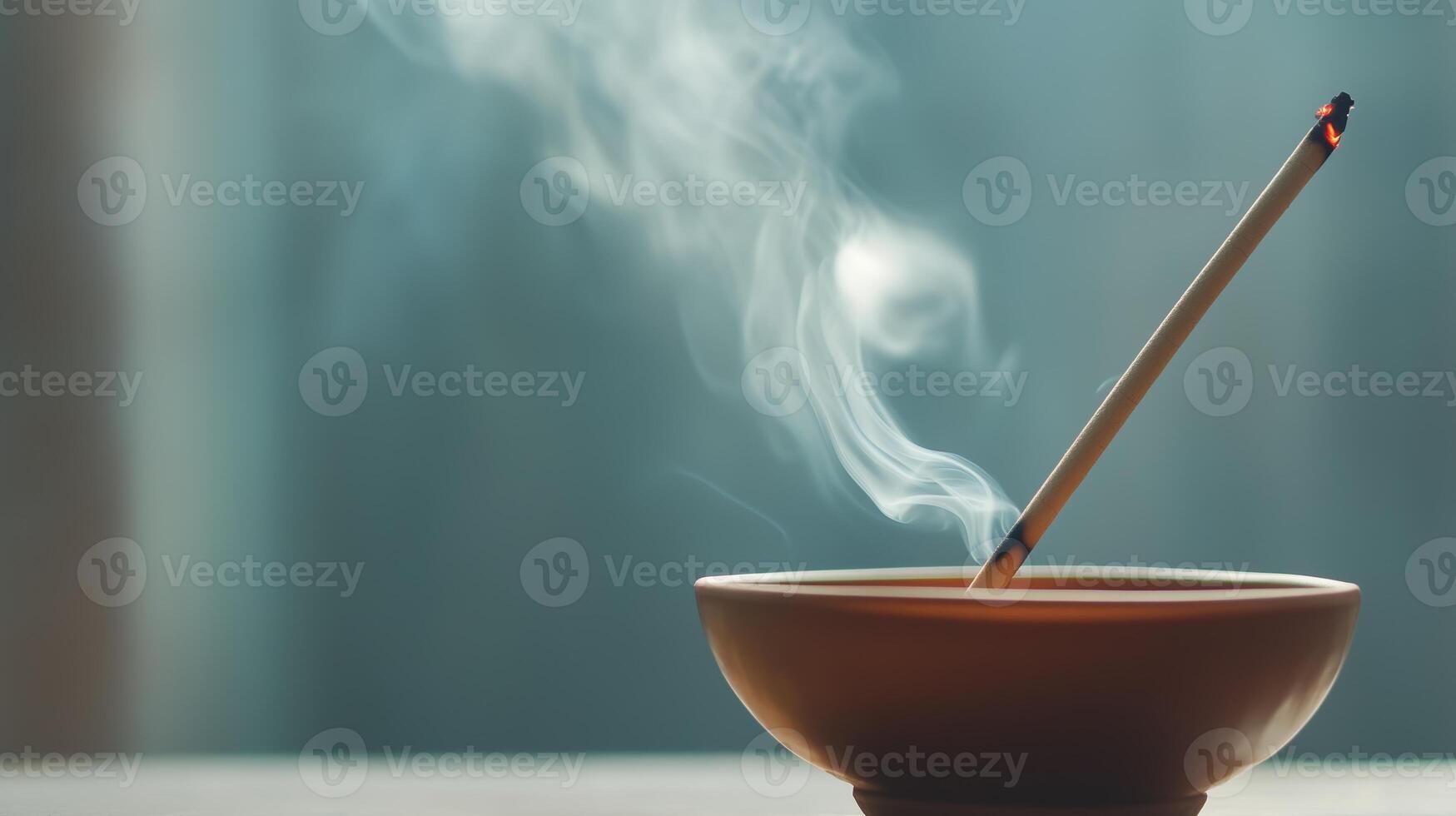 Incense stick burning in a ceramic holder with smoke wafting upwards in a serene setting photo