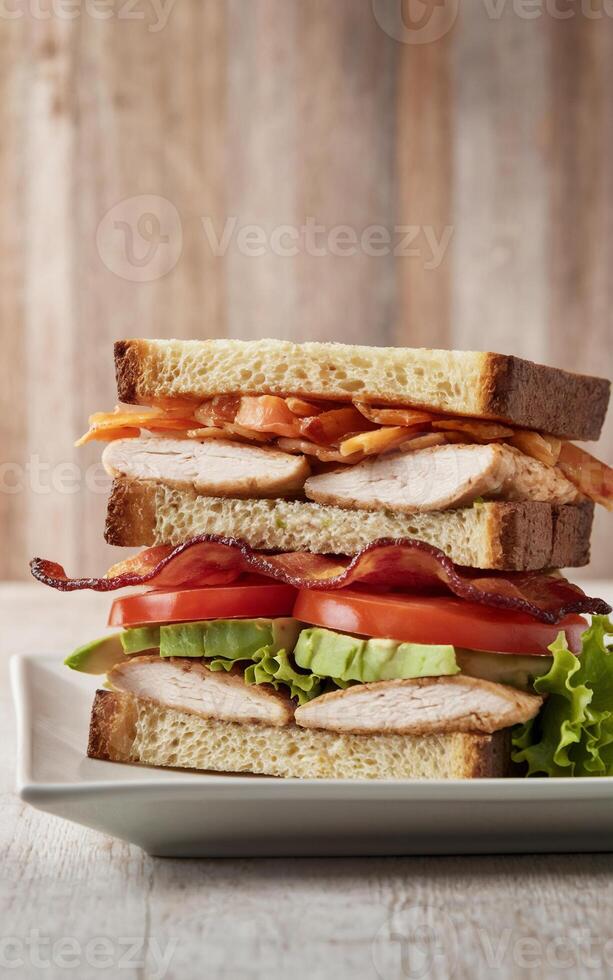 A hearty sandwich is stacked high with layers of crispy bacon, juicy tomato slices, fresh lettuce, and slices of tender chicken breast photo