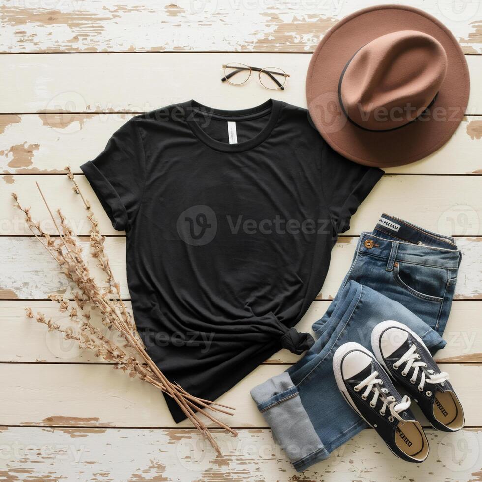 A stylish flat lay features a black t-shirt, denim jeans, and sneakers, with accessories including a brown hat and glasses. photo