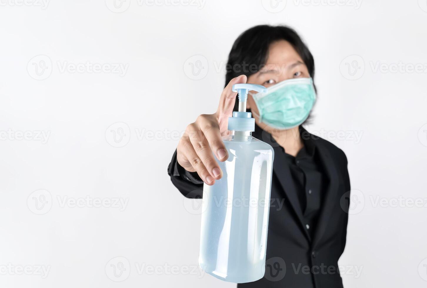 Asian mand holds a big blue gel alcohol pump bottle in front of him. An isolated man and object on the white clear screen in studio light. photo