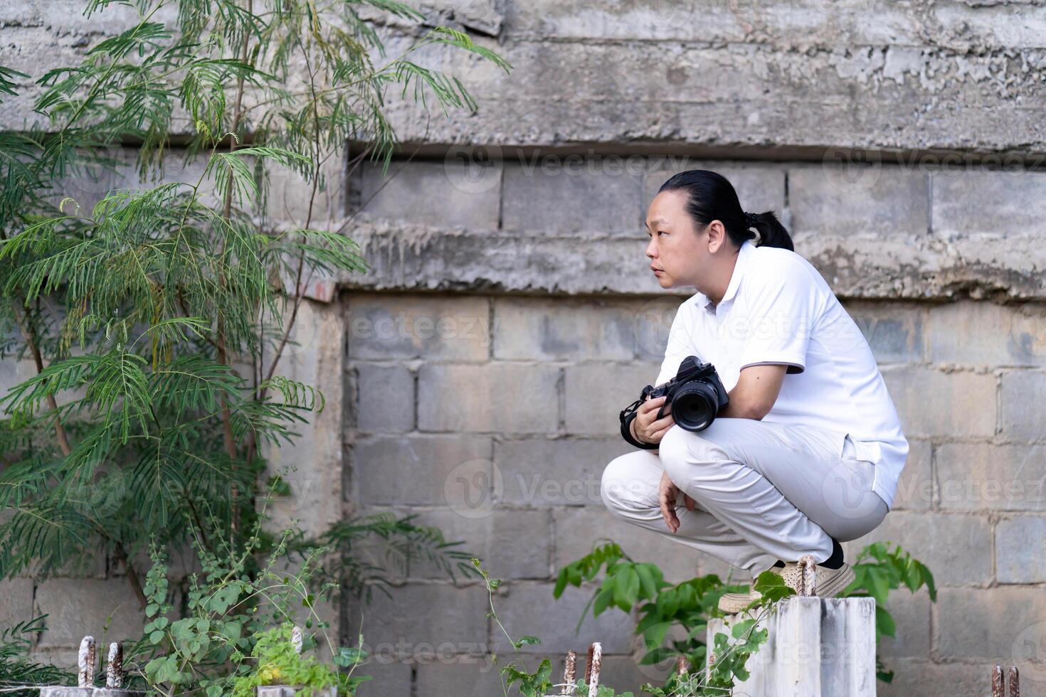 Asian Professional cameraman sits and thinks about 5how to create a creativity photo in the construction area background and environment.