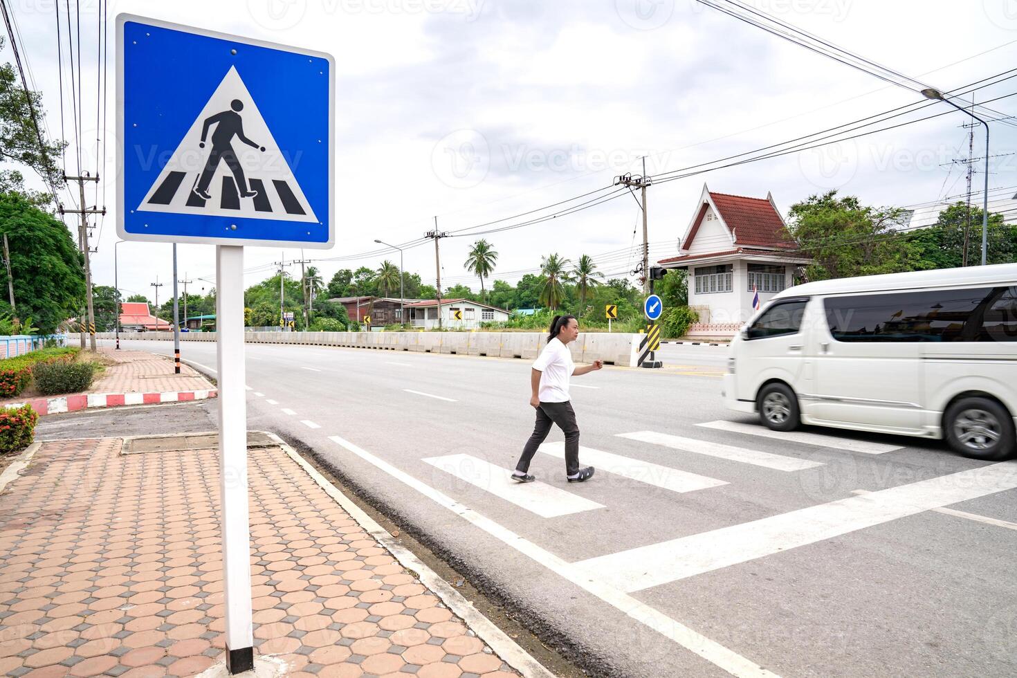 An Asian man prepares himself to walk and run 2across crosswalk to the other side, Thailand. photo