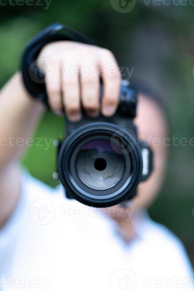 Asian man holds the Medium Format Camera in his 7hand and focus to shoot in front of him. photo