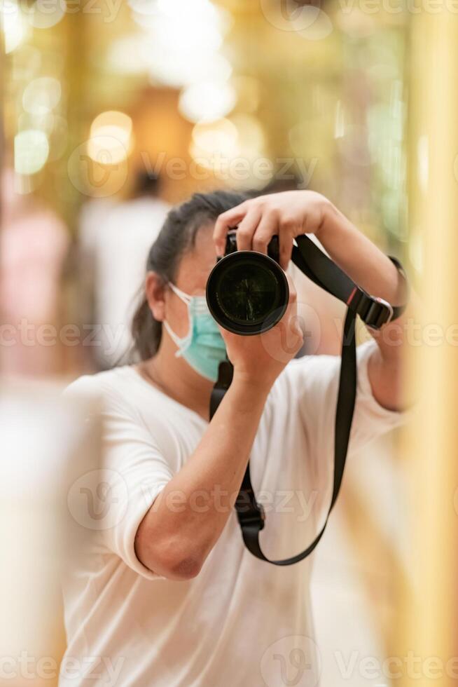 Photographer using camera to taking Self Portrait 2in the mirror.Photographer with a black SLR camera. photo