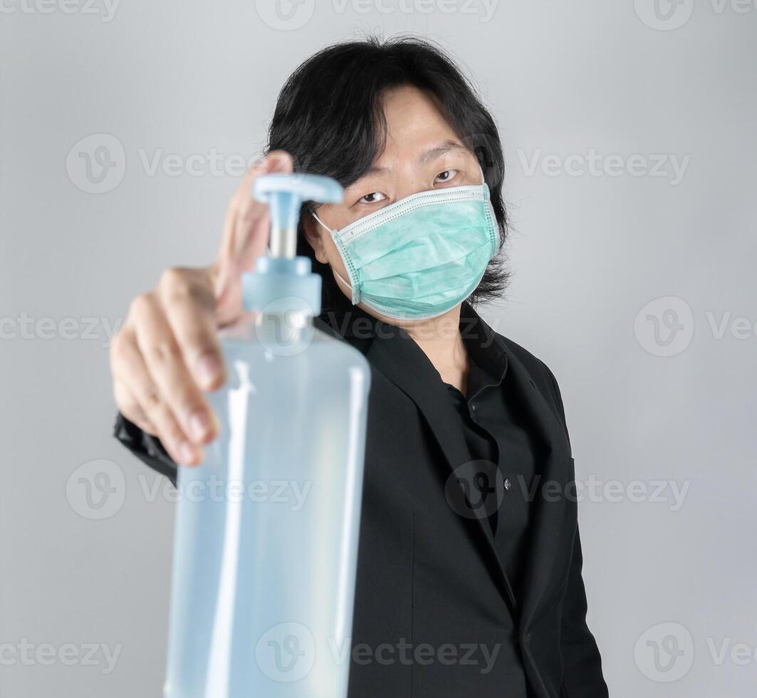 Asian mand holds a big blue gel alcohol pump bottle 1in front of him. An isolated man and object on the white clear screen in studio light. photo
