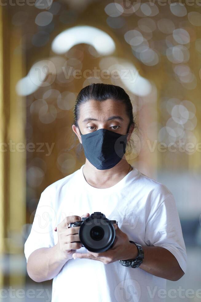 A man wearing black mask is shooting photo through a viewfinder camera with the right eye.33