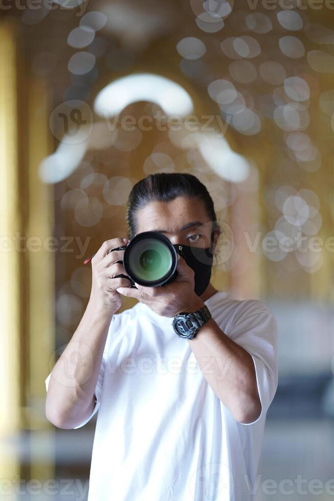 A man wearing black mask is shooting photo through a viewfinder camera with the right eye.2