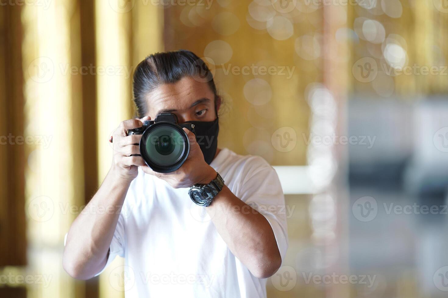 A man wearing black mask is shooting photo through a viewfinder camera with the right eye.1