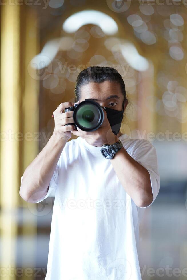 A man wearing black mask is shooting photo through a viewfinder camera with the right eye.3