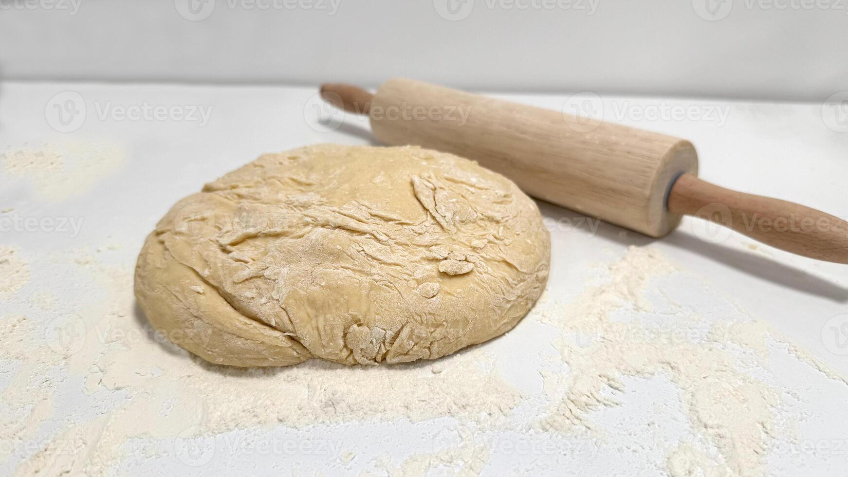 Dough Ball Ready for Rolling with Wooden Rolling Pin on Floured Surface photo