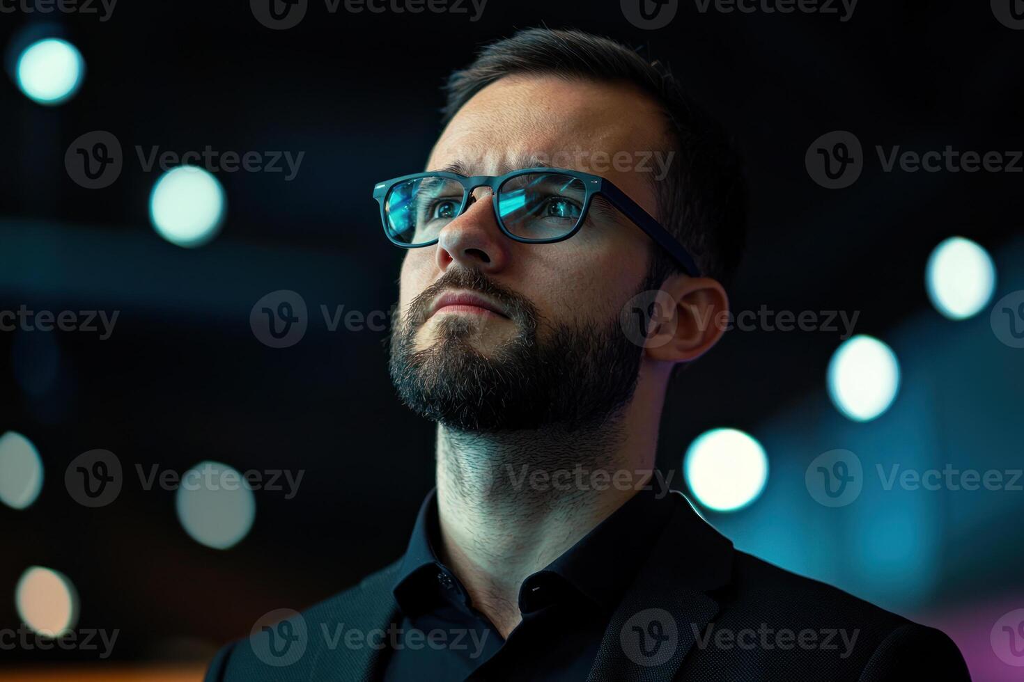thoughtful man with glasses and beard looks upward in dimly lit environment, with blurred bokeh lights in background photo