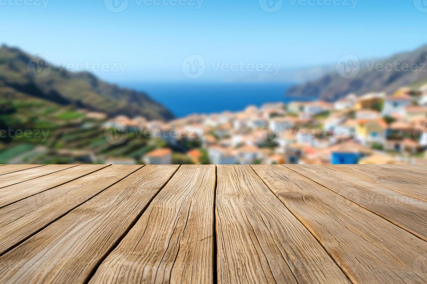 Rustic wooden tabletop overlooking blurred valley view of hillside village with colorful buildings and ocean behind.. photo