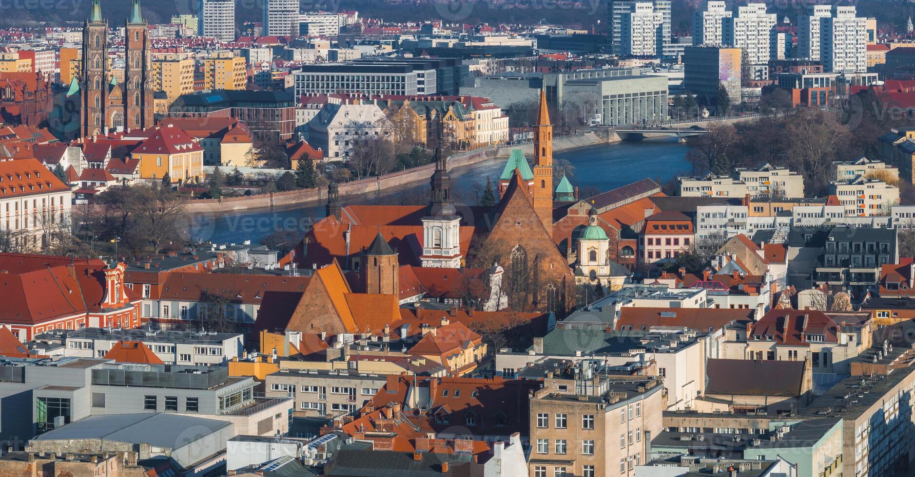 A vibrant aerial view of Wroclaw, Poland, featuring the Gothic Cathedral of St. John the Baptist, red roofed buildings, and the winding Oder River. photo