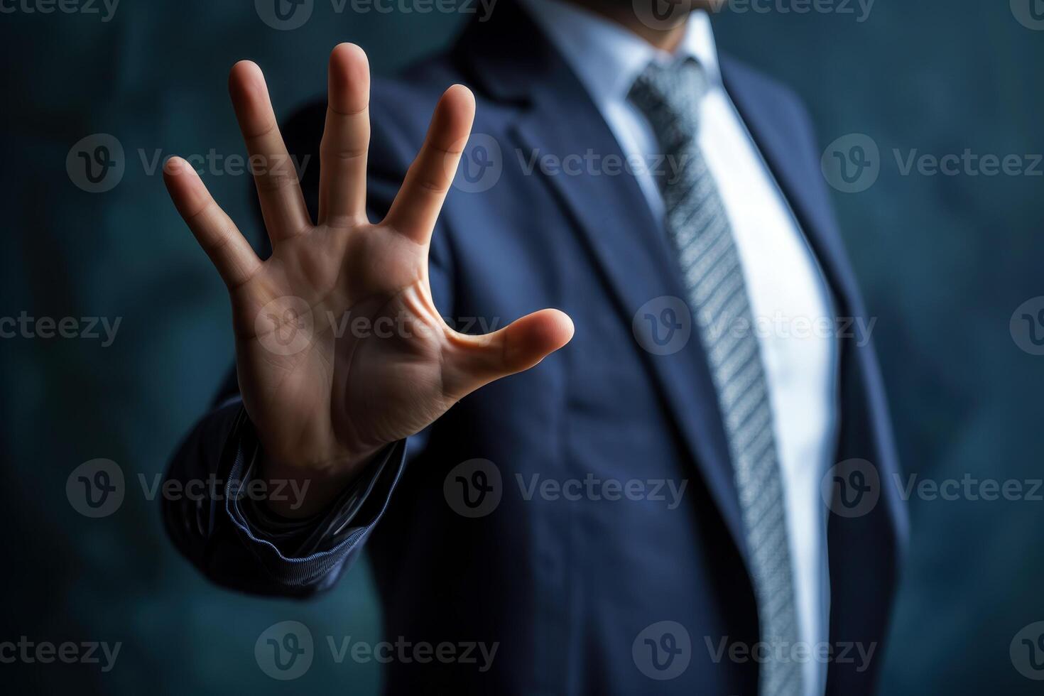 Businessman displays clear stop gesture in modern office. Confident hand signals halt to potential problems deals. Raised palm conveys firm decision warning. In formal setting. Blurred background. photo