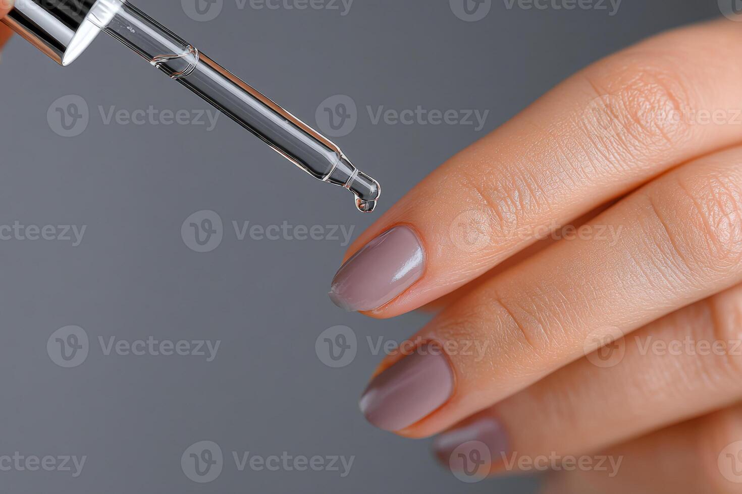 Dropper applying oil on fingernail closeup photo
