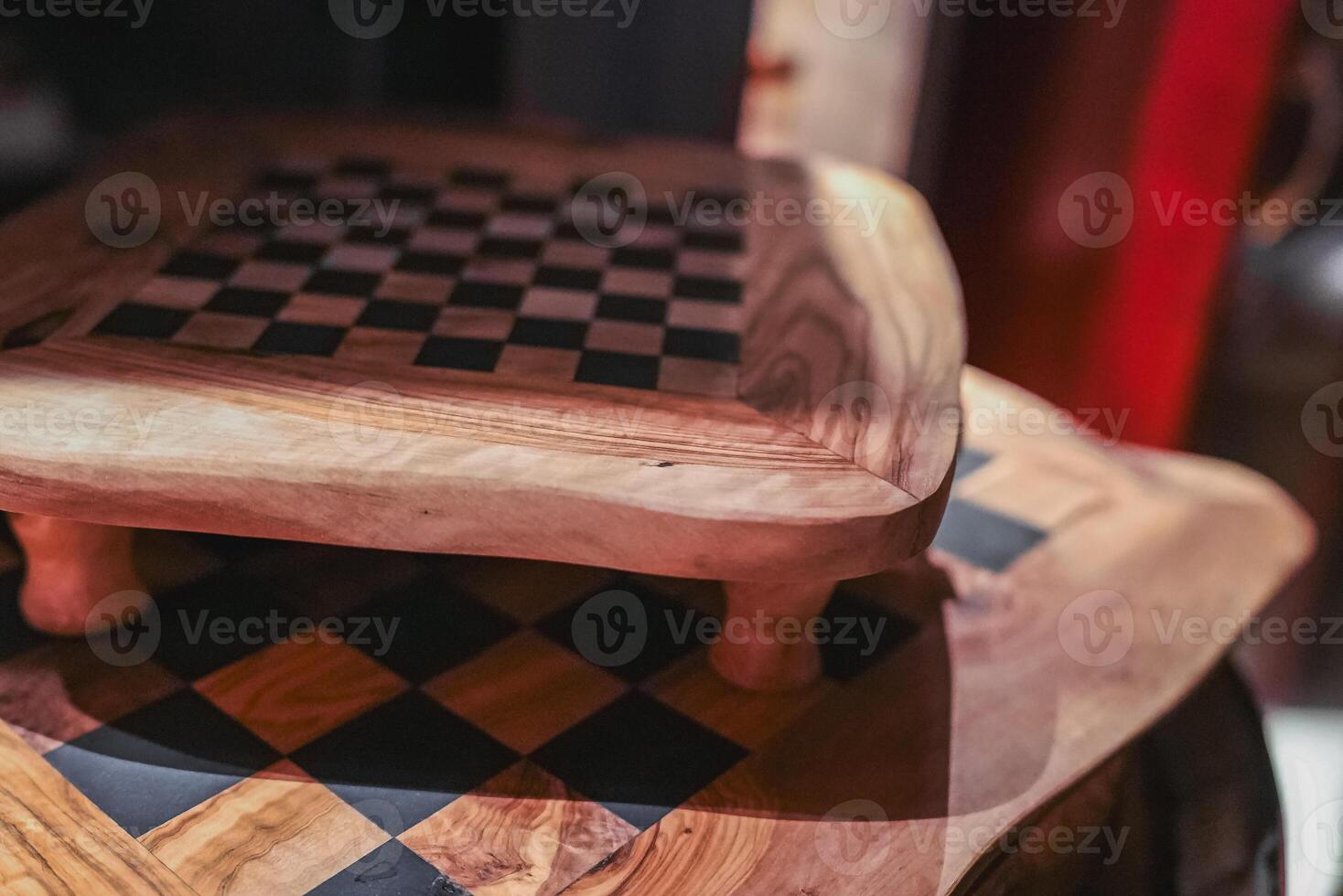 Two artisanal wooden chessboards with a black and wood checkered pattern, set in a refined interior with warm tones and intricate craftsmanship. photo