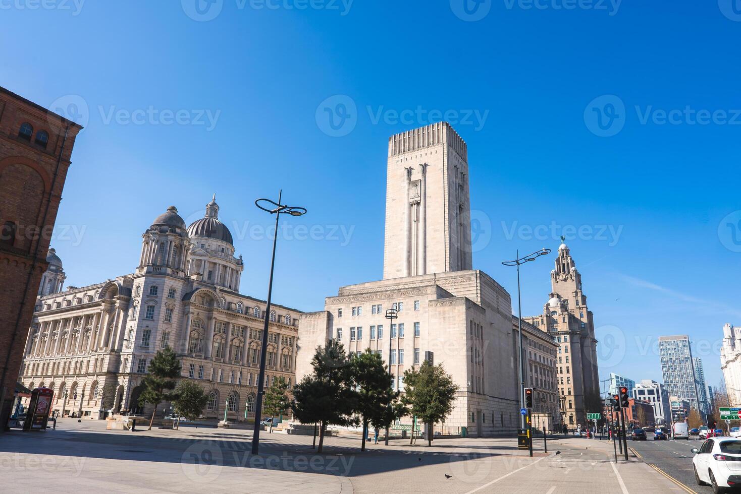 View of a Liverpool street featuring the Liver Building, Port of Liverpool Building, and George's Dock Ventilation Tower under a clear blue sky. photo