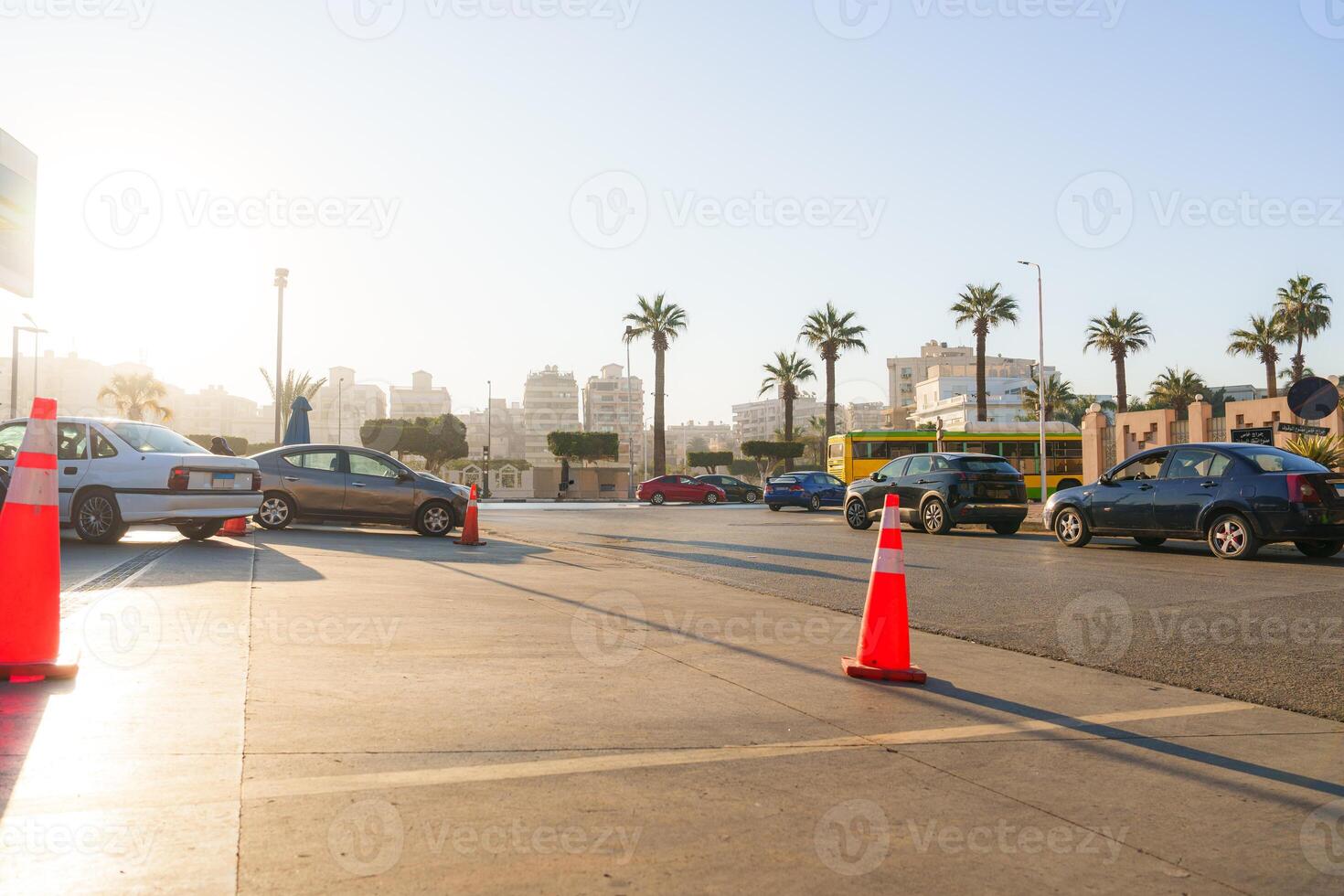 Cars navigating a busy urban intersection during golden hour with palm trees in the background photo