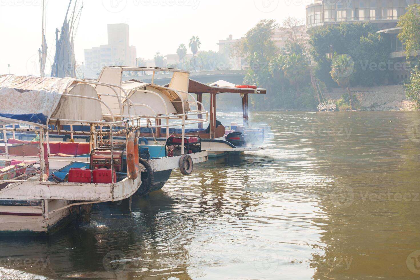 Boats navigate the river as mist envelops the banks in a tranquil morning setting photo