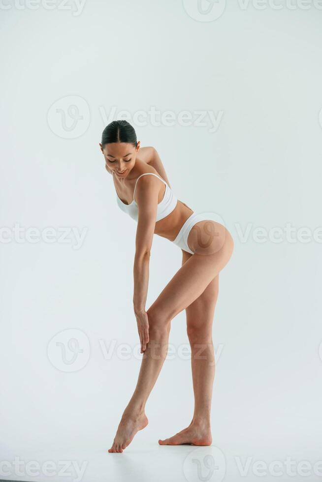 In the studio with white background. .Young woman with slim body type is in fitness clothes photo