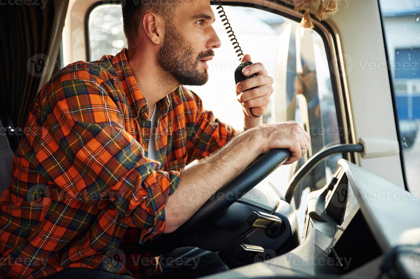 Side, view,, sitting inside the vehicle. Young truck driver in casual clothes photo