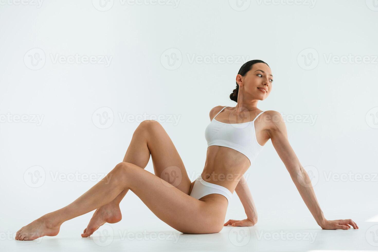 Taking a break,, sitting on the floor. Young woman with slim body type is in fitness clothes in the studio photo