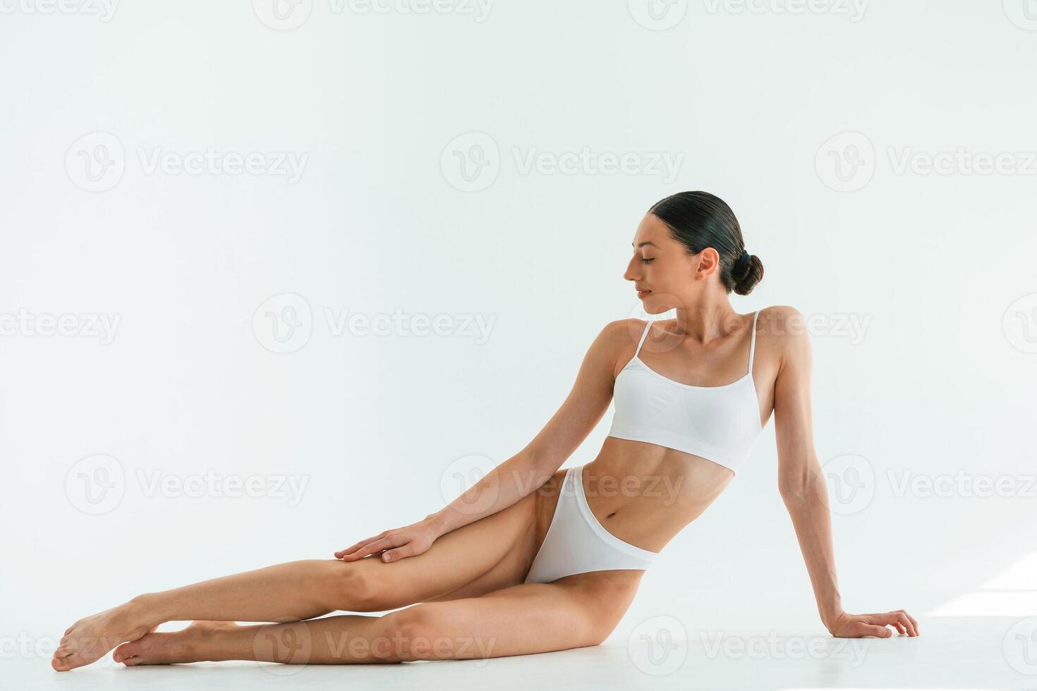 Taking, a, break, sitting on the floor. Young woman with slim body type is in fitness clothes in the studio photo