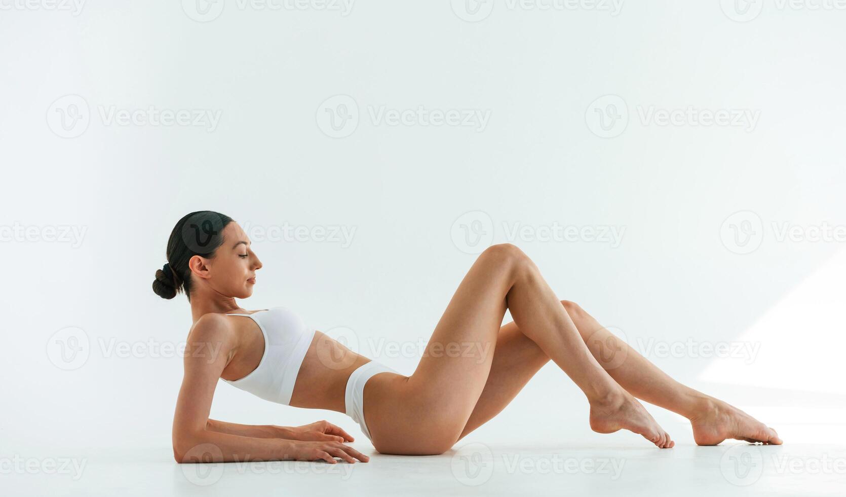 Side view, lying, down.. Young woman with slim body type is in fitness clothes in the studio photo