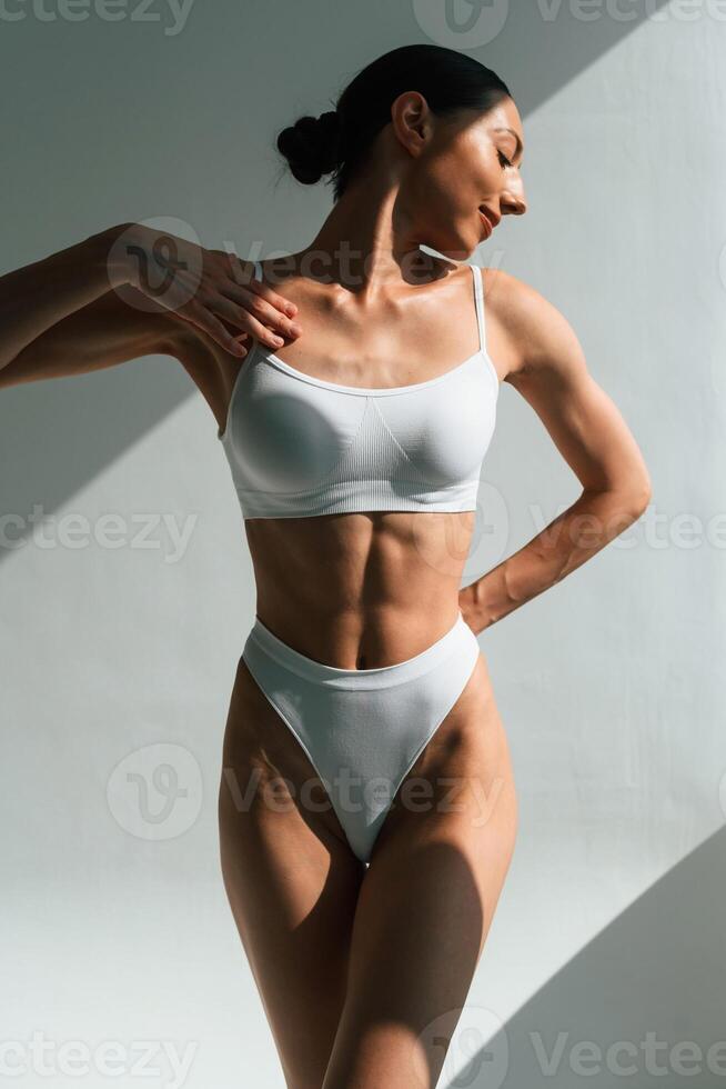 Shadow is on the body. Young woman in ,fitness clothes is in the studio photo